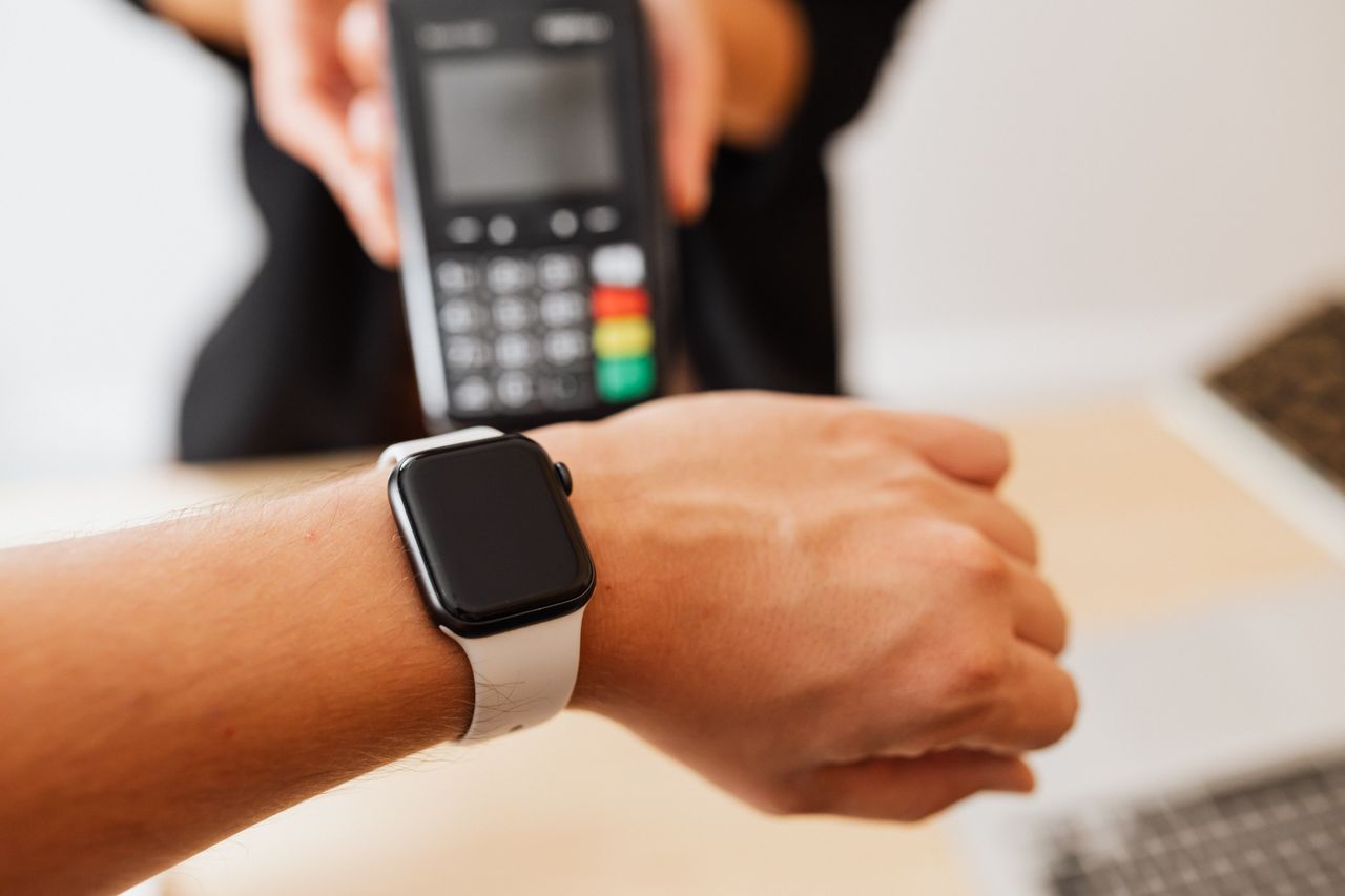 Services Person making a contactless payment using a smartwatch at a cashless checkout counter.