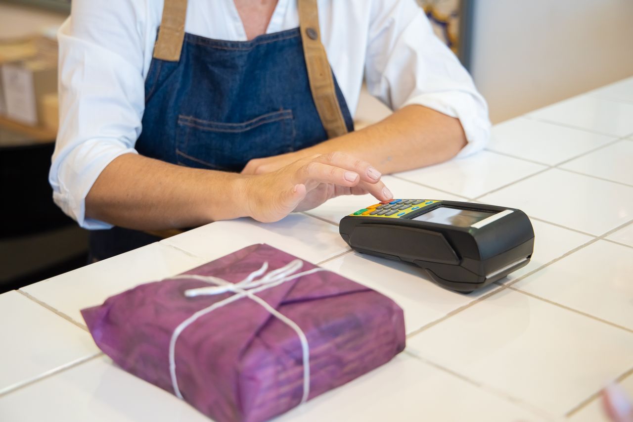 Services A person using contactless payment at a retail counter in Portugal wearing an apron.