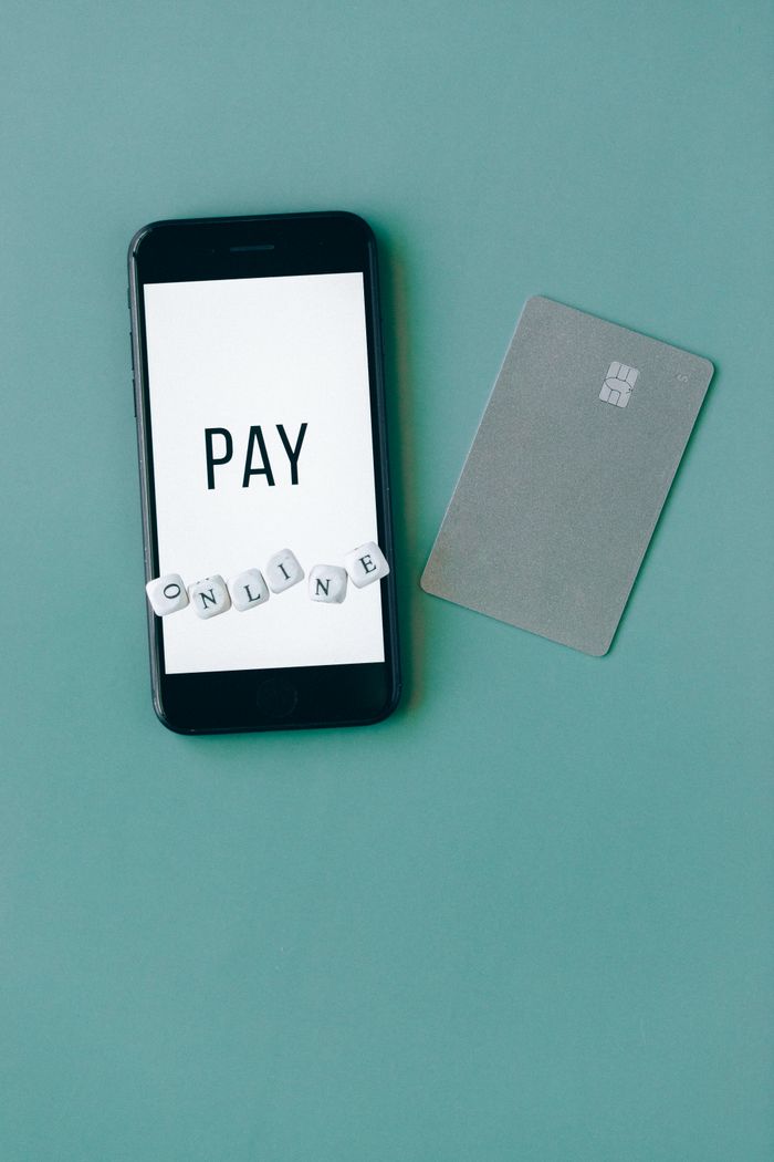 Services Vertical shot of a smartphone and card promoting online payment with a green background.