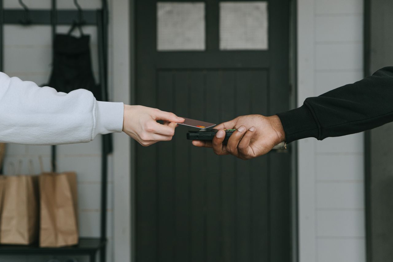 Services Close-up of hands making a contactless card payment indoors, highlighting cashless transaction technology.